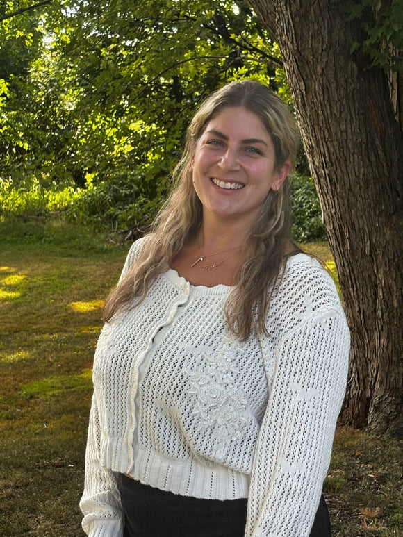 Stephanie Servideo smiling next to a tree on a sunny day.